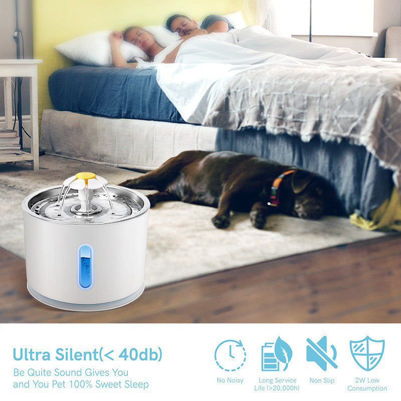 Dog lying on a bed next to a white pet water fountain with blue accents, in a bedroom setting.